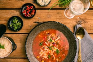 Top view of a delicious Mexican soup with sides of rice and herbs, perfect for a cozy meal.