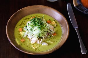 Vibrant green Mexican soup with fresh herbs in a rustic setting, perfect for authentic culinary presentations.